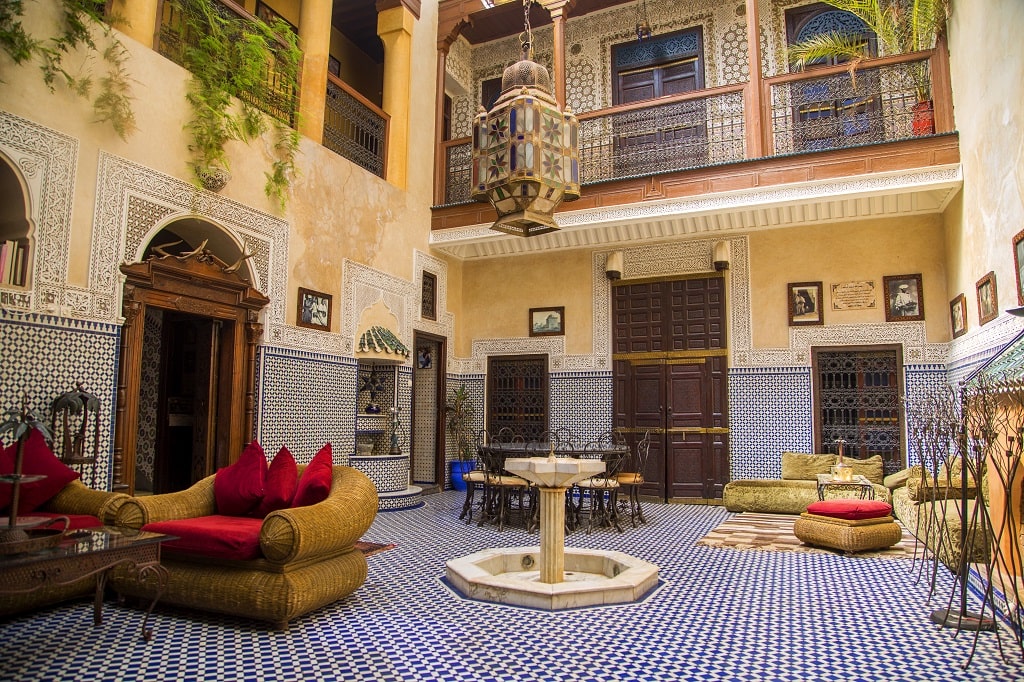The outdoor area, with a fountain, chairs, and tables, in the middle of a riad boutique hotel in Marrakech